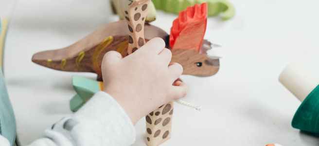 child holding brown and green wooden animal toys